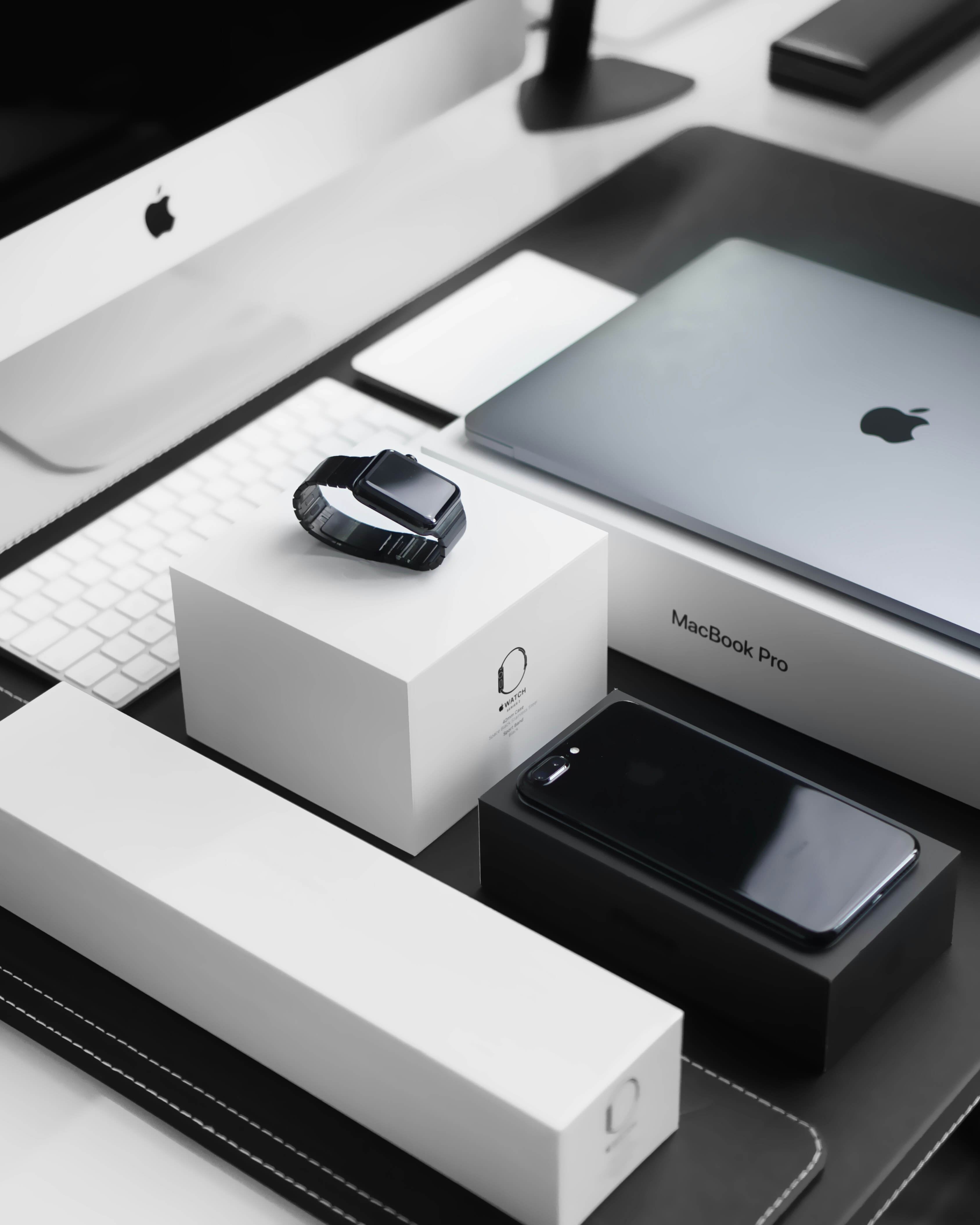 A collection of Apple products: an iPhone, mouse, charger, and earbuds